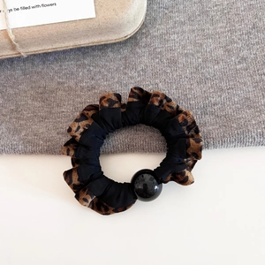 Detail of leopard print scrunchie with soft fabric texture and a glossy black bead detail