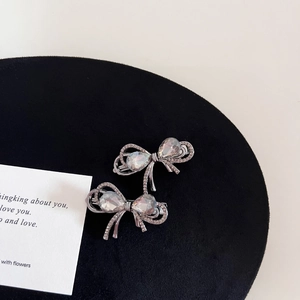 Close-up of gunmetal bow hair clips with shimmering rhinestones on black velvet