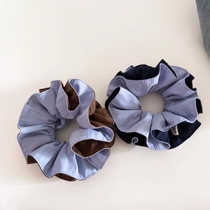 Detailed texture of dual-tone scrunchies in light blue and brown fabric on white background