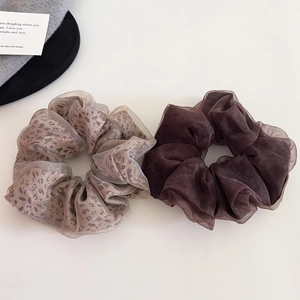 Detailed close-up of leopard print and dark brown organza scrunchies on white surface