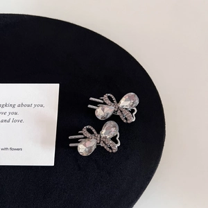 Macro detail of gunmetal butterfly hair clips with sparkling rhinestones on black velvet