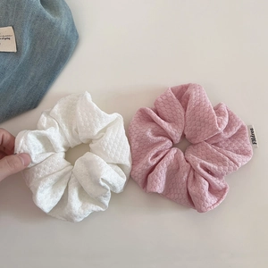 Detailed view of cream-colored bubble knit hair scrunchies in white and pink textured fabric
