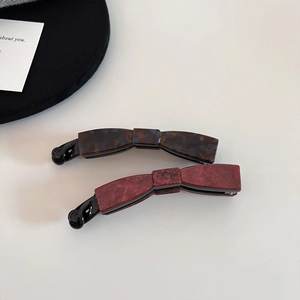 Detail view of tortoiseshell and marble texture acetate bow banana hair clips