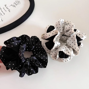 Close-up of black and white polka dot satin hair scrunchies with soft silk texture