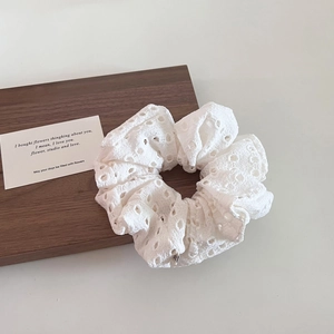 Detailed view of white hollow lace scrunchie with intricate floral crochet patterns
