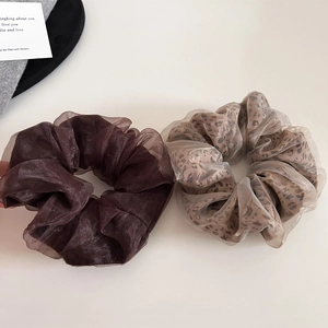 Detail view of leopard print and brown organza scrunchies on a minimalist background