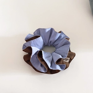 Detail of blue and brown dual-color scrunchie with a stylish brand woven label