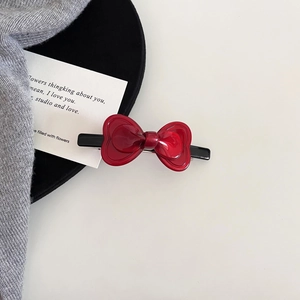 Detail view of a glossy red bow hair clip featuring a high-shine acetate finish
