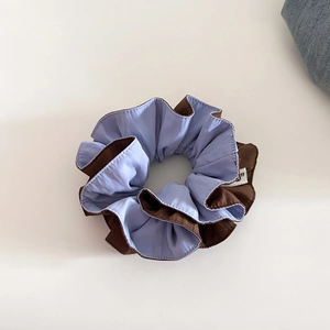 Close-up of minimalist two-tone blue and brown scrunchie with silky pleated texture