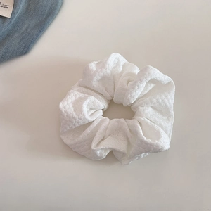 Detailed macro view of the cream-colored textured knit fabric on this elegant scrunchie