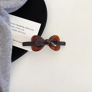 Detail view of a tortoiseshell acetate bow hair clip with glossy finish and metal base