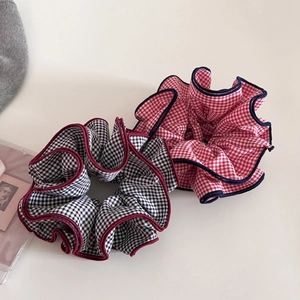 Detail of two layered checkered scrunchies with contrast edges in black and red patterns