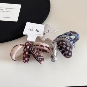 Detail of knitted elastic hair bands with polka dots and geometric patterns on a white base