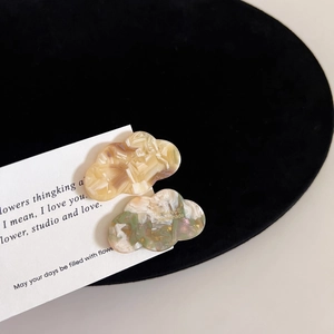 Detail of cloud-shaped acetate hair clips with marble texture and gold lettering