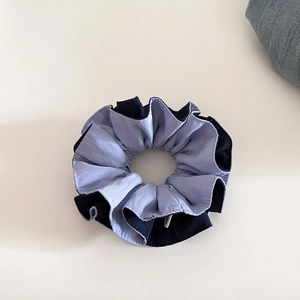 Detailed macro view showing the two-tone blue fabric texture of the elastic hair scrunchie