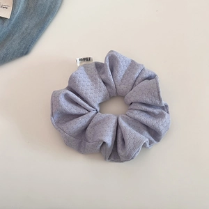 Detail of light purple bubble knit scrunchie featuring a white FMdrea brand tag on its edge