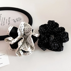 Close-up of elegant black and white polka dot scrunchie set made of soft satin fabric