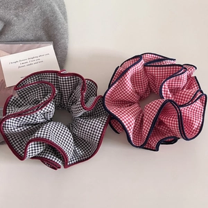 Detailed view of plaid scrunchies in red and black gingham patterns with contrast edges