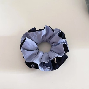 Detail shot of two-tone fabric scrunchie with neat decorative stitching and ruffled edges