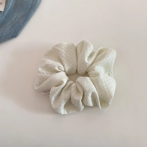 Close-up of pearl white knitted scrunchie showing detailed textured fabric and soft material