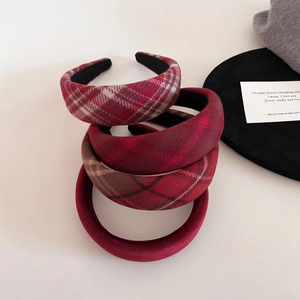 Close-up of assorted red plaid and velvet padded headbands for a vintage elegant look