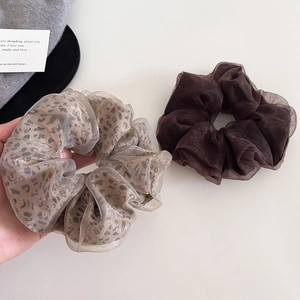 Detailed view of leopard print organza scrunchies in cream and dark coffee colors