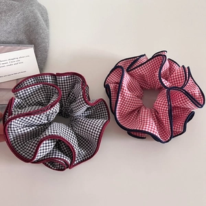 Detail view of large checkered hair scrunchies with contrasting stitched edges and textures