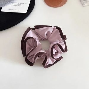 Détail d'un grand chouchou rose avec bordure marron contrastée et texture plissée chic