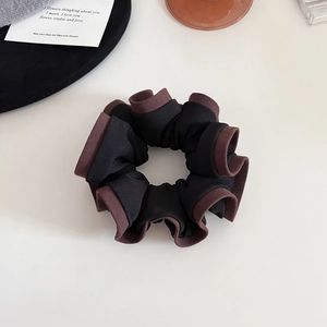 Détail du chouchou bicolore noir et marron avec un design élégant à bords ondulés