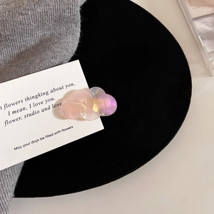 Detail of cloud-shaped acetate hair clip with iridescent pearl finish and handmade logo