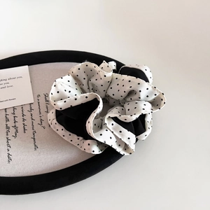 Detailed view of layered black and white polka dot scrunchie on a stylish display tray