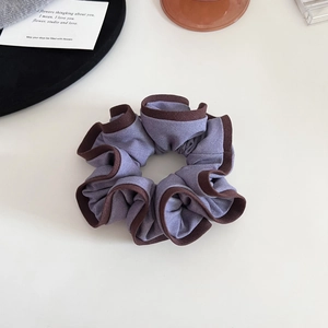 Vue détaillée du chouchou en tissu violet avec bordure marron café sur fond blanc pur