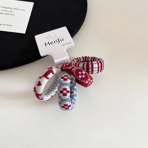 Close-up of four knitted hair ties with polka dots and stripes on a display card
