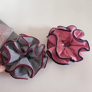 Detail of two-piece plaid scrunchies with contrast edges in red and black checkered patterns