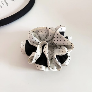Detailed close-up of a satin scrunchie featuring elegant polka dot and solid black panels