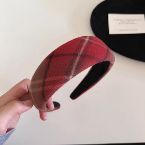 Close-up of red plaid thick sponge headband with classic wool texture for autumn
