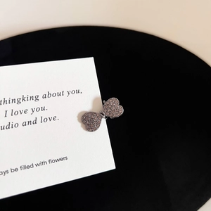 Detailed macro view of heart-shaped hair clip with champagne rhinestones on gunmetal base
