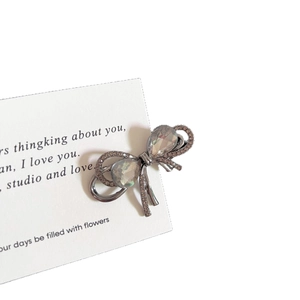 Elegant gunmetal bow hair claw with rhinestones and iridescent gems on a white card