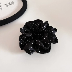 Close-up of black satin scrunchie with white polka dots for an elegant vintage style hair look