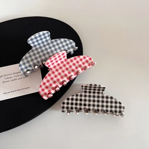 Close-up of three checkered acetate hair claws in blue, red, and black patterns
