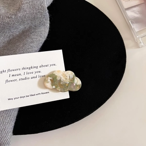 Macro view of cloud-shaped acetate hair clip with marble texture and gold handmade stamp