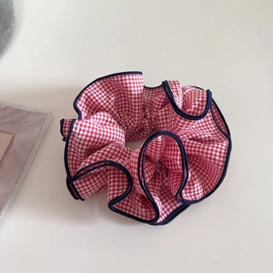 Detail of red gingham oversized scrunchie with navy blue contrast piping edges