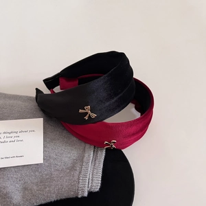 Close-up of velvet headbands in black and burgundy with gold bow metallic accents