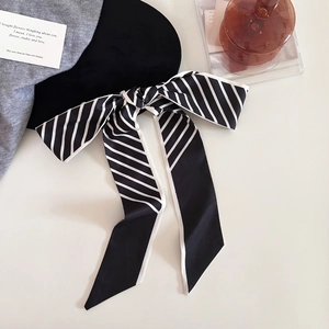Détail d'un béret noir en laine orné d'un élégant nœud en ruban à rayures noires et blanches