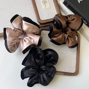 Three elegant satin scrunchies with velvet edges in pink, brown, and black colors