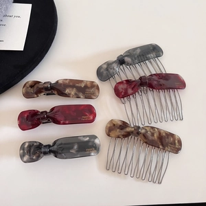 Close-up of tortoise shell and marble acetate hair clips and combs set with gold metal details