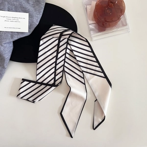 Détail d'un élégant foulard étroit en satin à rayures noires et blanches