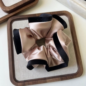 Detail view of large champagne satin scrunchie with elegant black velvet trim contrast
