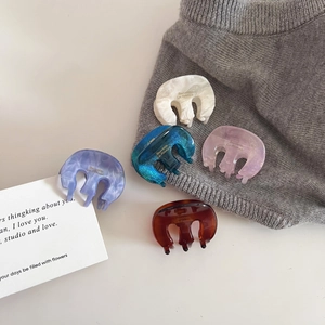 Set of five mini acetate hair claws in pastel colors with marble texture on grey knit