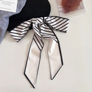 Gros plan d'un foulard étroit en soie à rayures noué en nœud élégant pour les cheveux